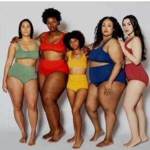 FIVE PLUS SIZE MODELS IN TWO-PIECE BATHING SUITS IN GREEN, RED, YELLOW, NAVY BLUE, AND BURGANDY.