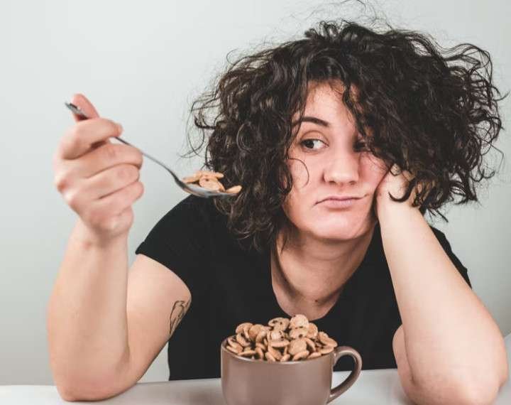 LADY IN BLACK TY-SHIRT - BINGEING ON A CUP OF MUNCHIES