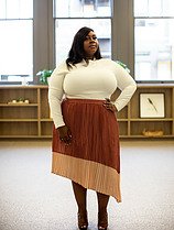 FULL SIZE - POSING WEARING FITTIED BROWN PLEATED SKIRK WOTH LONG SLEEVE WHITE TOP AND HANDS ON HER HIP