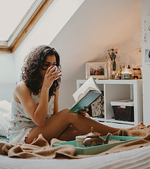SELF-CARE - YOUNG LADY RELAXING AT HOME, READING A BOOK, SIPPING TEA