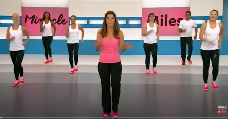 LESLIE SANSONE IN HER WALKING STUDIO. SHE IS DRESSED IN A HOT PINK TANK TOP AND BLACK LEGGINGS. AS BEAUTIFUL AS EVER.