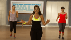 LESLIE SANSOME IN A BLACK STRETCH WORKOUT OUTFIT WITH A LIGHT YELLOW SLEEVELESS TOP