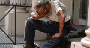 man covering his facw sitting on steps from heat exhaustion