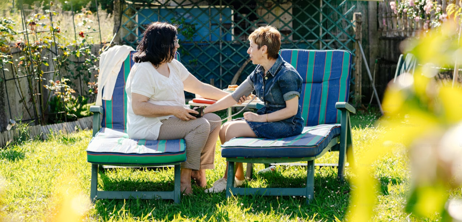 DOCTOR AND PATIENT SIT OUTSIDE AS PATIENTS HAS HER BLOOD PRESSURE CHECKED