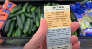 A SHOPPER IS READING ABOUT PRODUCE FACTS WHILE SHOPPING