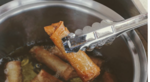 THIS IS A POT OF SPRING ROLLS COOKED IN HOT OILS USING A PRONGS