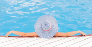 SUNBATHER WEARING A WIDE BRIM HAT ENJOYING A COOL DIP IN THE WATER