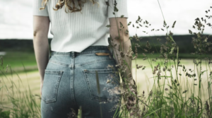 WOMEN WEARING A WHITE SHORT SLEEVED TOP AND A PAIR OF PLUS SIZE DENIM JEANS STANDING NEAR A GARDEN