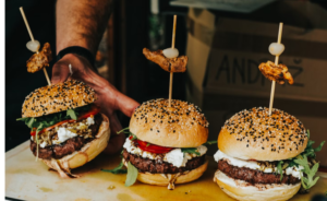 PERSON AT A RESTAURANT SERVING THREE PLANT-BASED BURGERS