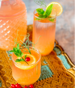 PEACH-COLORED NON-ALCOHOLIC DRINKS WITH MINT AND ORANGE SLICE AS A TOPPING