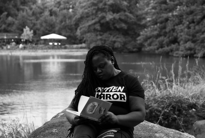 TREATING SEPARATION ANXIETY SHOWN IN THIS BLACK AND WHITE PHOTO OD A YOUNG LADY WITH BLACK T-SHIRT READING A BOOK OUTDOORS NEAR A LAKE 